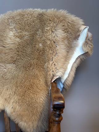 sheep coat in colour caramel hanging over antique wooden chair