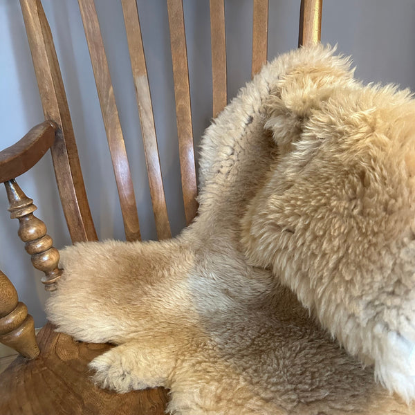 a sheep coat lying on a wooden chair in colour caramel